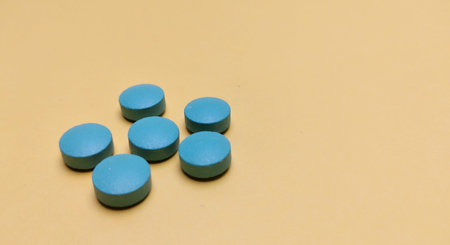 Blue pills on a yellow background. Focus on foreground, soft bokeh.の写真素材