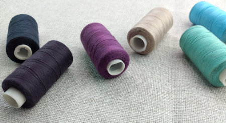 spools of thread on a linen tablecloth, sewing accessories.
