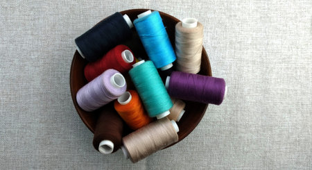 Spools of multicolored thread in a bowl on a gray backgroundの写真素材