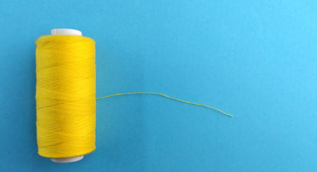 Yellow thread spool on blue background. Space for your text.の写真素材