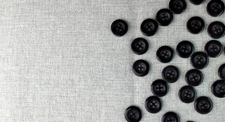 Black sewing buttons on a linen background with copy space, top view
