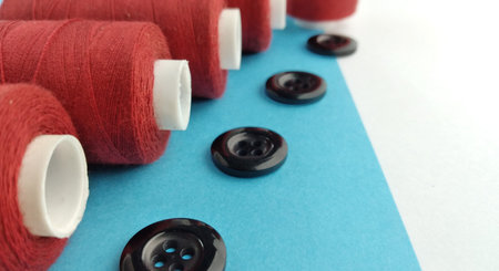 Spools of thread and buttons on a blue and white background.の写真素材