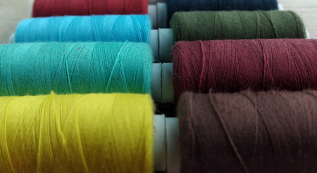 Sewing threads of different colors in a box on a wooden background