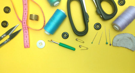 Sewing accessories on a yellow background. Sewing tools, scissors, thread, needles, pins, measuring...