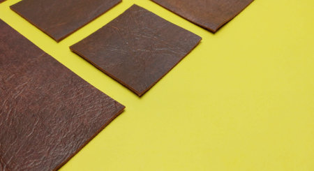 Brown leather samples on yellow background. Top view with copy space.の写真素材
