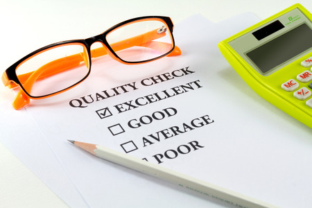 paper with word quality check and white pencil eyeglasses calculator with mark on excellentの写真素材