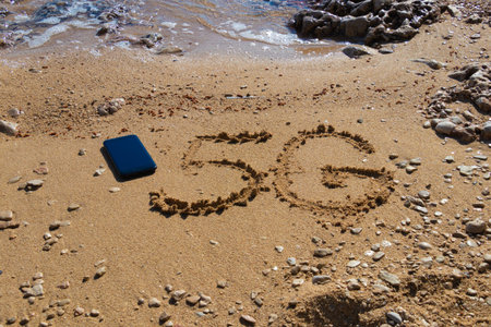 5G written on the sandy beach with sea waves and smart phone
