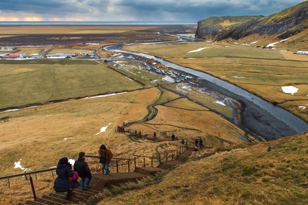 SKOGAFOSS, ICELAND - DECEMBER 30, 2015 : Travelers climb up steps to see this view point from above, you also can walk right up the river. Fantastic and a quick visit just a 5 min walk to the falls.のeditorial素材
