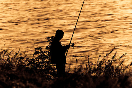 Silhouette of Fisherman on sunset.の写真素材