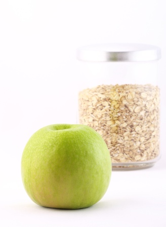 Healthy nourishment: oat flakes and green apple isolated on whiteの写真素材
