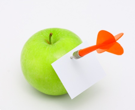 Dart in the green apple on white backgroundの写真素材