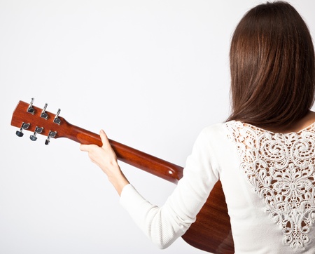 Young brunette playing guitar; isolated on neutral backgroundの写真素材