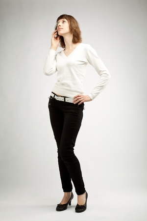 The slim young woman speaking on the cellphone; neutral backgroundの写真素材