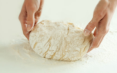 Kneading dough; close-up of female hands in flour kneading dough