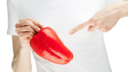 Woman holding fresh red sweet pepper and pointing at it: healthy eating or diet concept; isolated on whiteの写真素材