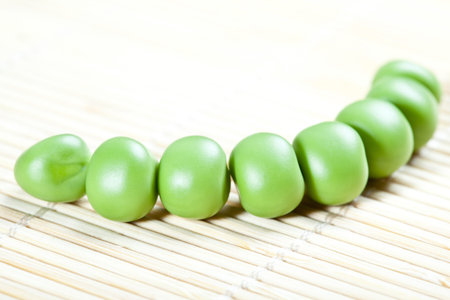 Green pea balls in a row on a bamboo background