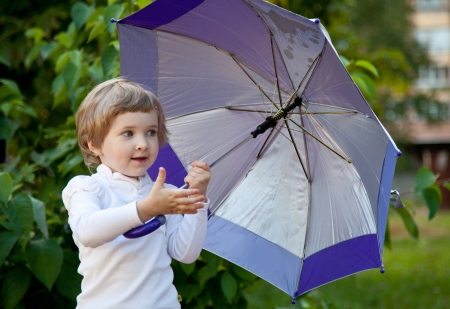 Happy little girl with umbrella in a summer parkの写真素材