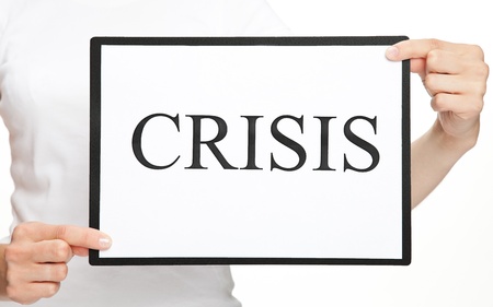 Woman's hands holding clipboard with word CRISIS on white sheet of paperの写真素材