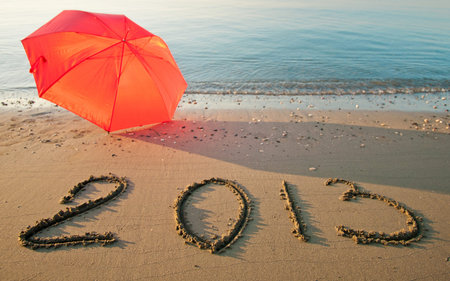 Peaceful seashore with umbrella and 2013 drawn on  sandの写真素材