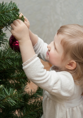 Smiling little girl decorating a Christmas treeの写真素材
