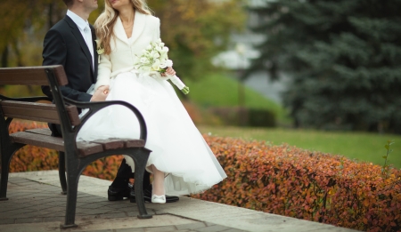 A new married couple sitting on a bench in autumn parkの写真素材