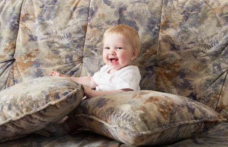 Happy baby girl sitting on a sofaの写真素材