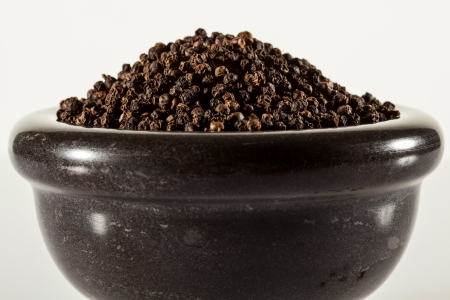 Black peppers in a clay pot on neutral backgroundの写真素材