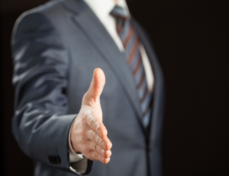 Businessman offering handshake to you on black backgroundの写真素材