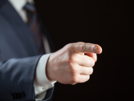 Businessman pointing forward on dark backgroundの写真素材