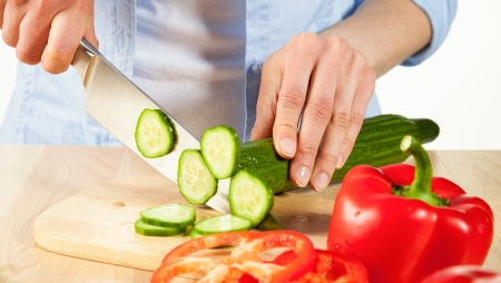 Salad preparation - cutting into pieces red pepper and cucumberの写真素材