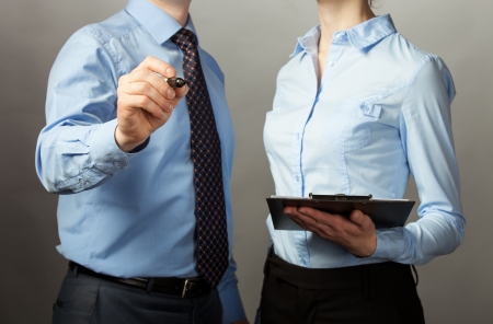 Businessman and businesswoman discussing a plan of work, grey backgroundの写真素材