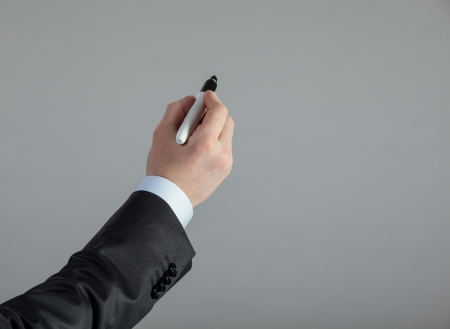 Businessman's hand writing something on a grey wallの写真素材
