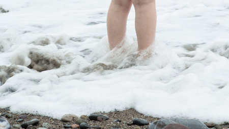 Legs of a little girl in foamy sea waterの写真素材