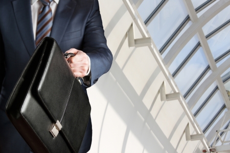 Unrecognizable businessman walking with a briefcase in a modern officeの写真素材