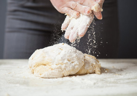 Woman's hands knead dough on a table