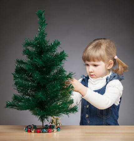 Beautiful little girl decorates the Christmas treeの写真素材