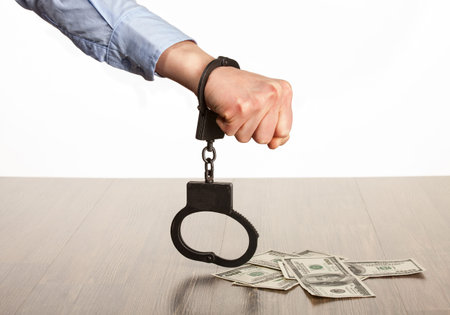 Hands in handcuffs and money  on the table; white background