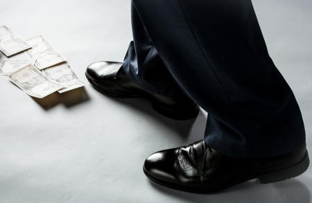 Feet of man in black shoes going by money trackの写真素材
