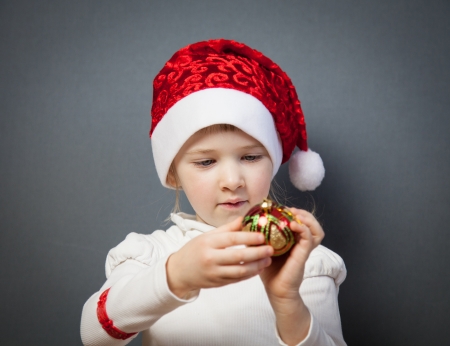 Portrait of a charming little girl in Santa's hat, grey backgroundの写真素材