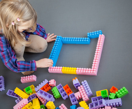 Little girl constructing with construction set, grey backgroundの写真素材