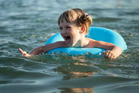 Smiling little girl swimming with inflatable circle