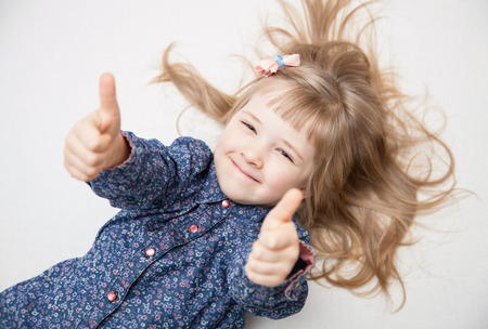 Smiling little girl showing thumb up - closeup portraitの写真素材