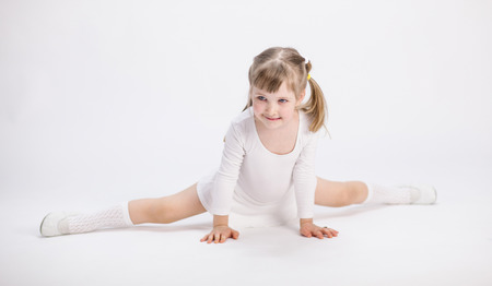 Smiling little girl doing the splits on white backgroundの写真素材