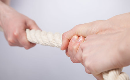 Hands pulling a rope ton grey background