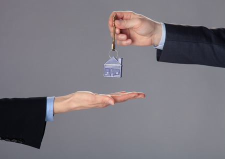 Unrecognizable businessman passing a key to woman's hand, closeup shotの写真素材
