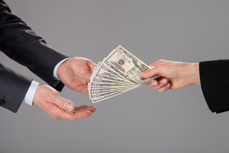 Businessman's hands accepting an offer of money on grey backgroundの写真素材