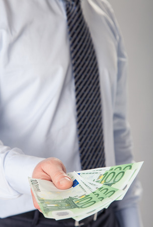 Unrecognizable businessman giving euro banknotes to youの写真素材