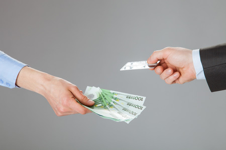 Business people exchanging credit card and money - closeup shot of handsの写真素材