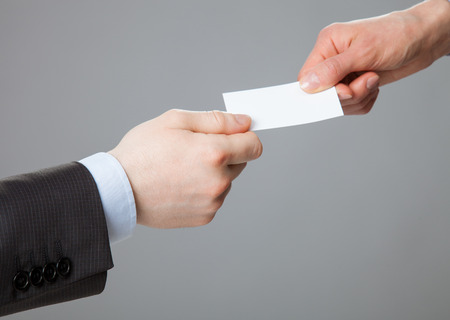 Business people exchanging business card on grey backgroundの写真素材