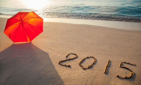 Peaceful seashore with umbrella and 2015 drawn on  sandの写真素材